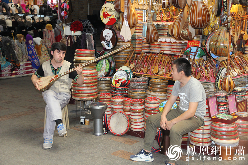 烏魯木齊二道橋巴扎內(nèi),店主正在向客人展示樂器。楊文遠 攝