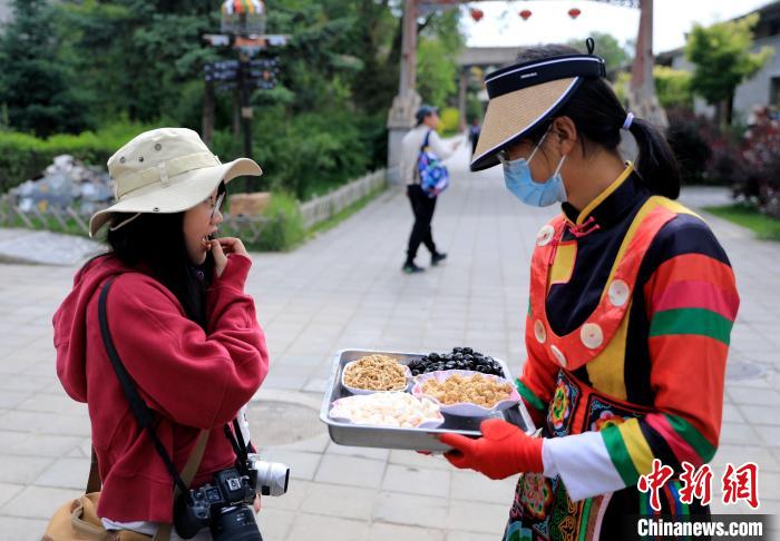 圖為身穿土族服飾的女性介紹當(dāng)?shù)靥厣〕浴!⊙Φ?攝 圖為身穿土族服飾的女性介紹當(dāng)?shù)靥厣〕浴!⊙Φ?攝